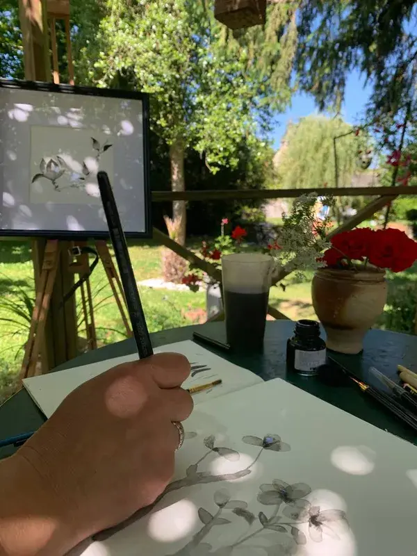 Atelier d'aquarelle en plein air : peinture de fleurs sur un chevalet dans un jardin.