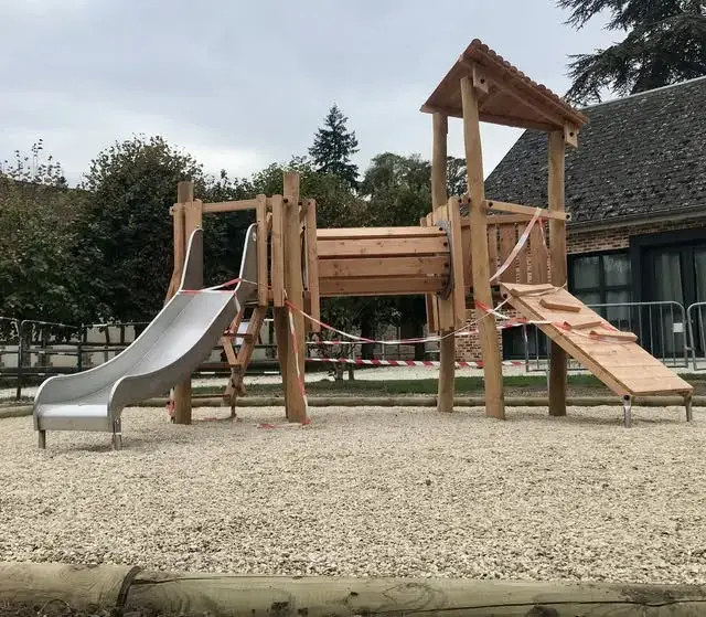 La nouvelle structure de jeu en bois avec toboggan métallique, sur la place du village, devant l'école.