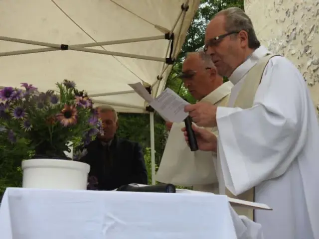 Homme en aube près d'un bouquet de fleurs