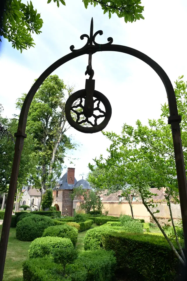 Arche en fer forgé ouvrant sur un jardin taillé