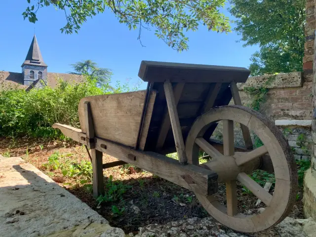 Brouette en bois ancienne devant le clocher de l'église
