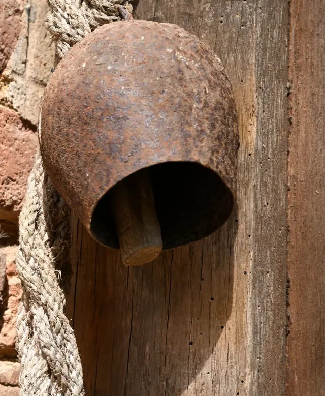 Cloche ancienne en fonte fixée sur un poteau de bois