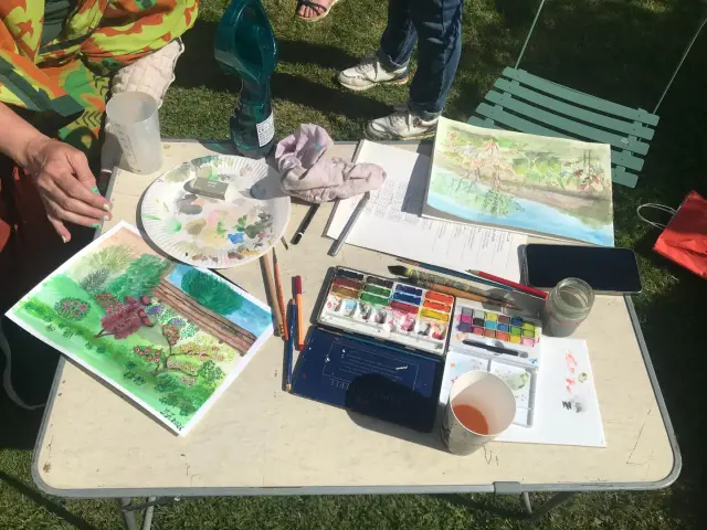 Fête de la Peinture : boîte d'aquarelle, pinceaux et esquisses posés sur une table
