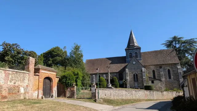 Le porche en brique, le monument aux morts et l'église en arrière-plan