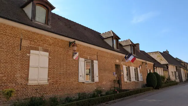 Rue du village bordée de maisons en brique, drapeaux tricolores