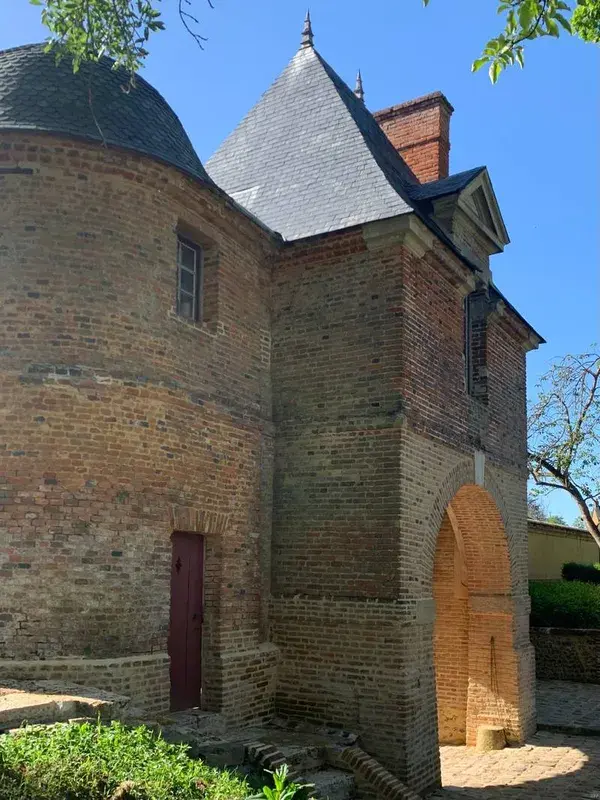 Tour en brique coiffée d'ardoise et son porche cintré, patrimoine bâti du village.